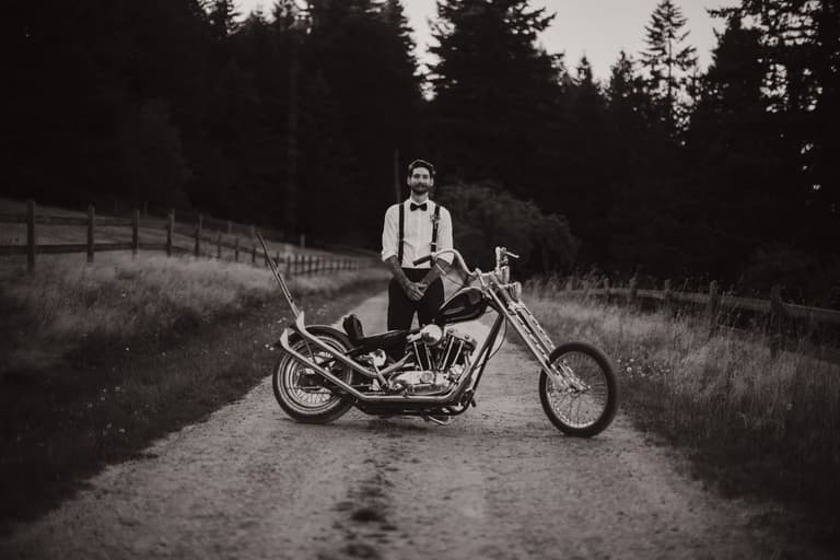 Groom standing beside a vintage motorcycle