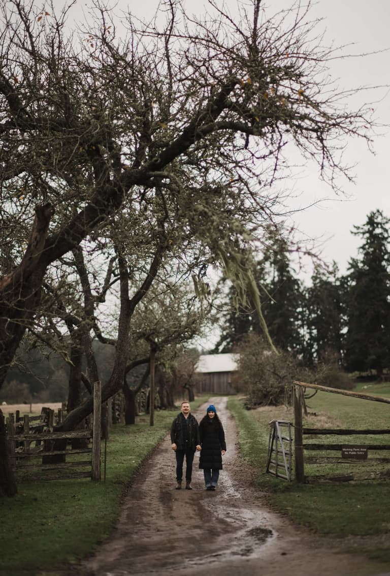 Newlyweds pausing for a kiss beneath old orchard trees
