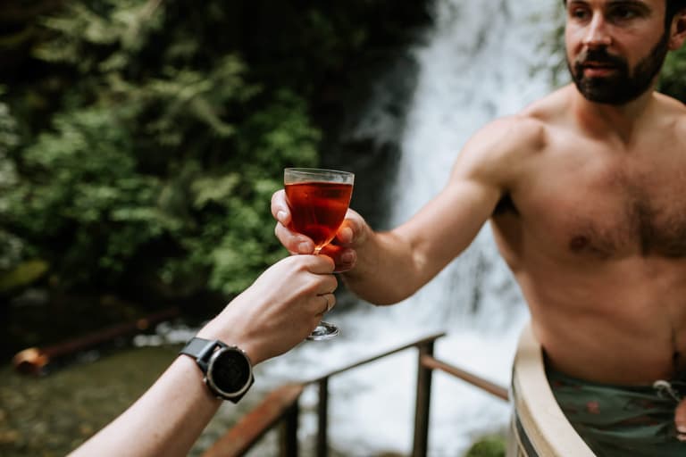 Toasting with wine before a rushing waterfall