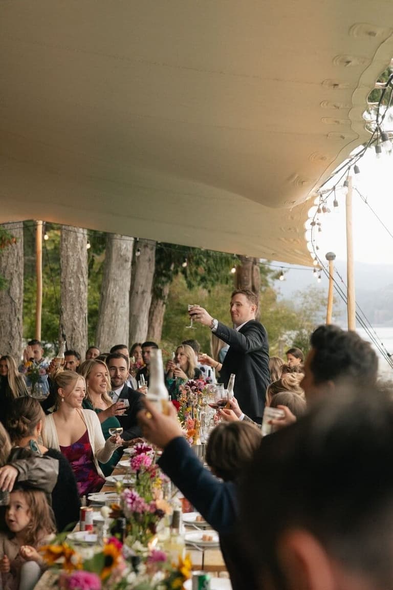 Groom raising a toast at a tented Taku Resort reception