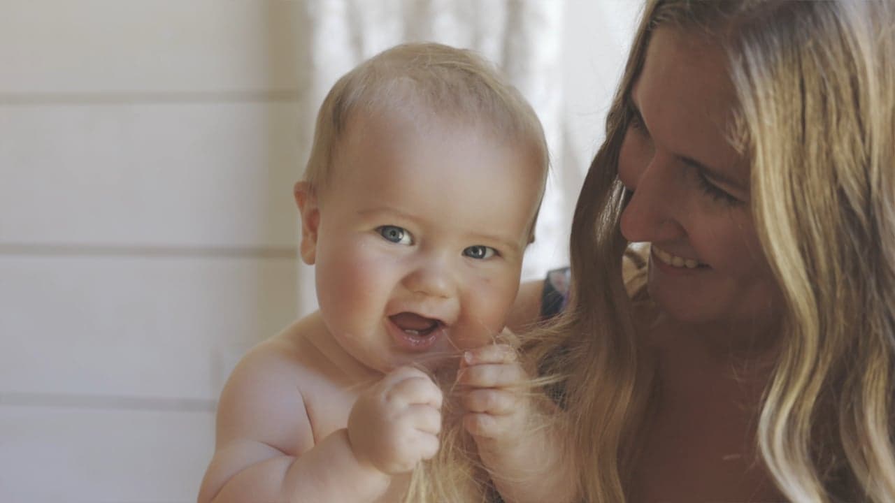 Laughing toddler grasps woman's long hair during a candid moment at Bullock Lake Farm wedding