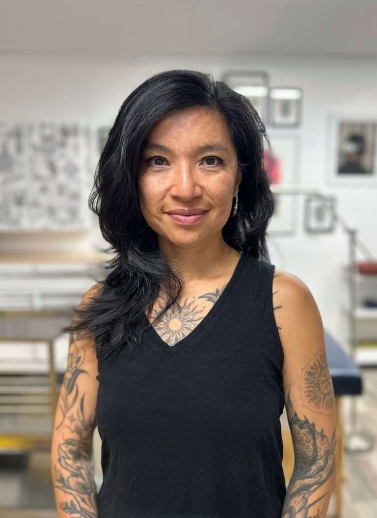 Tattoo artist Anh Le standing in her studio with framed artwork