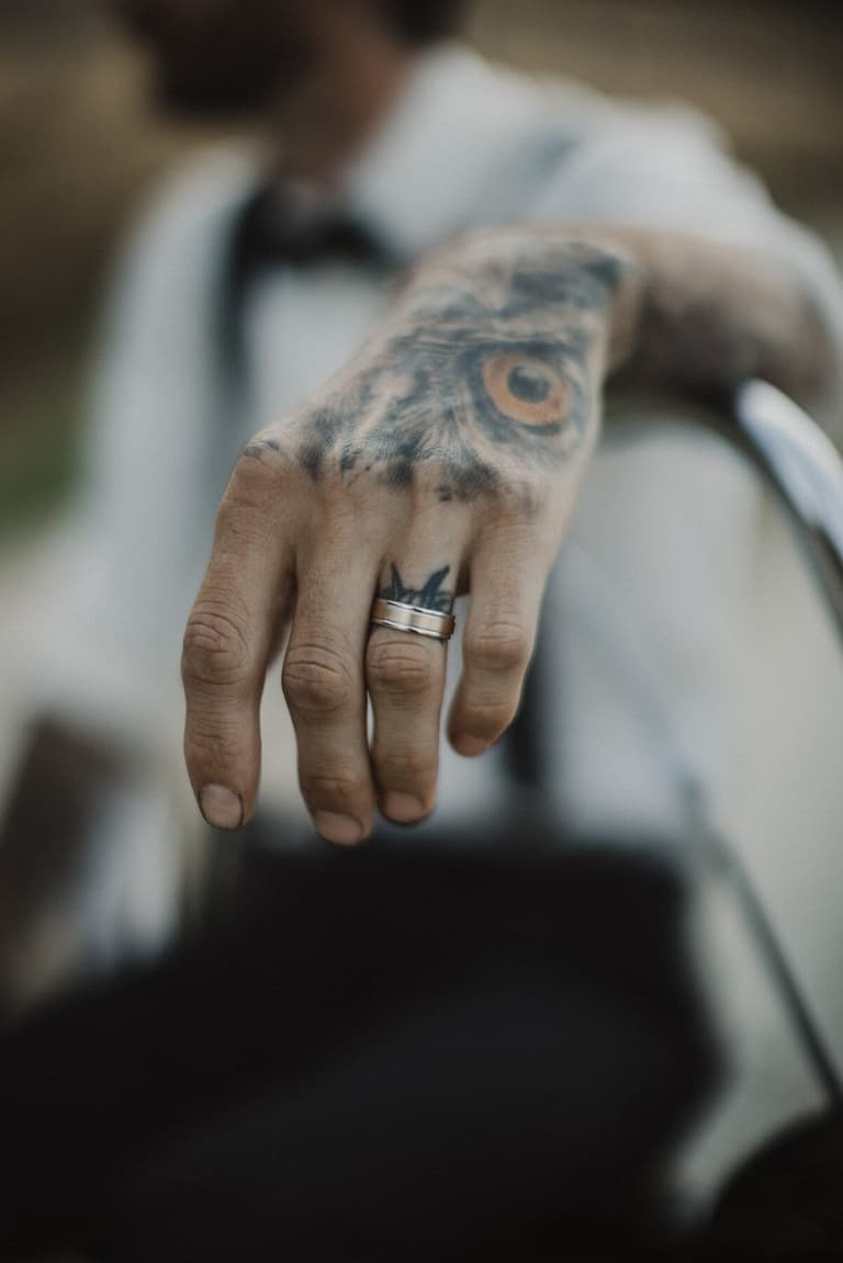 Groom's tattooed hand showing off a new wedding band