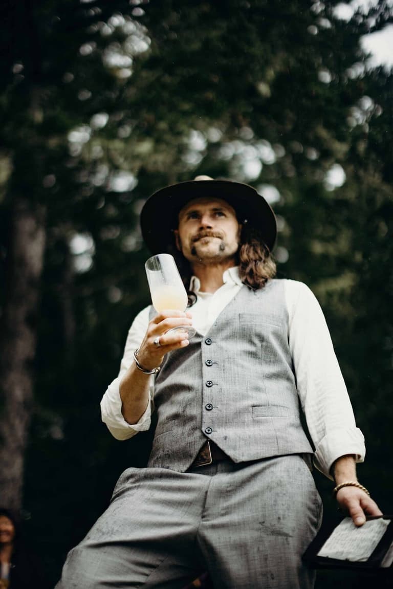 Vest-clad guest in a wide-brimmed hat sipping a cocktail