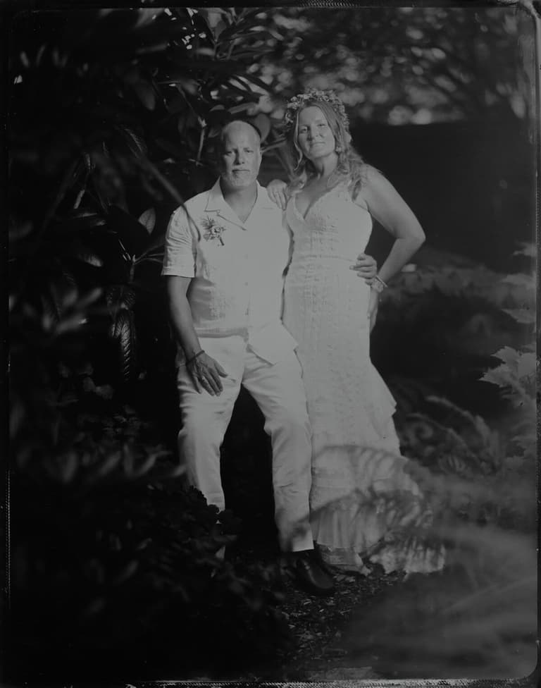 Couple dressed in white surrounded by tropical foliage, tintype