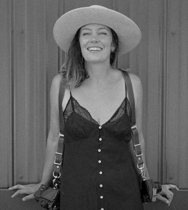 Photographer Jessica Kirkwood in a wide-brim hat with twin cameras