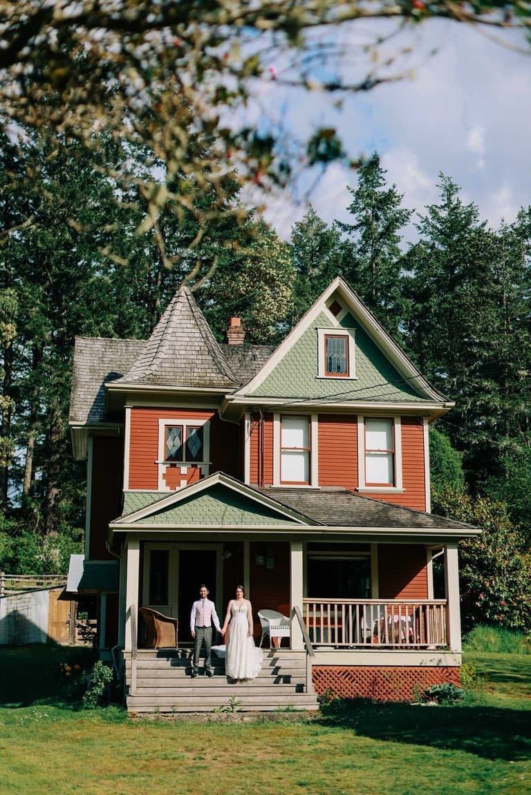 Couple on the front steps of the historic red Victorian farmhouse