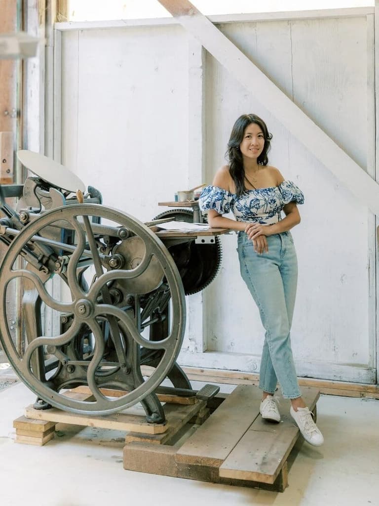 Stationer leaning on an antique letterpress at The AYLA View