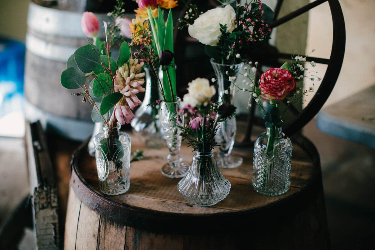 Crystal bud vases of flowers atop a wine barrel