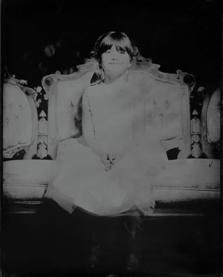 Young flower girl perched on an ornate parlour settee