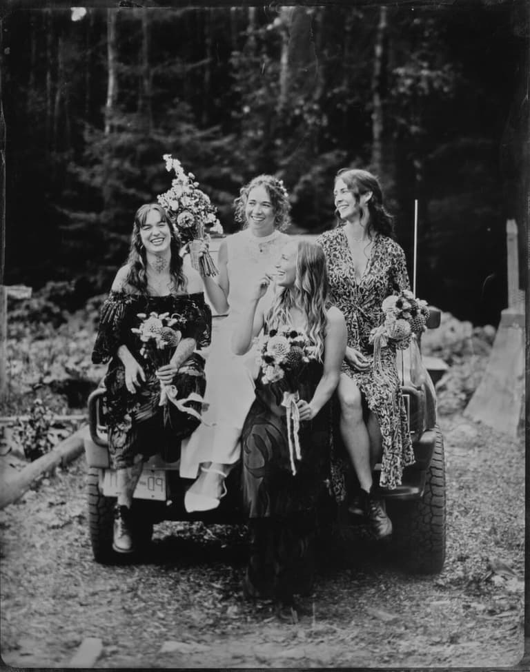 Bride and friends with bouquets piled on a jeep tailgate