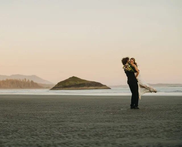 Newlyweds embrace on Long Beach in Tofino