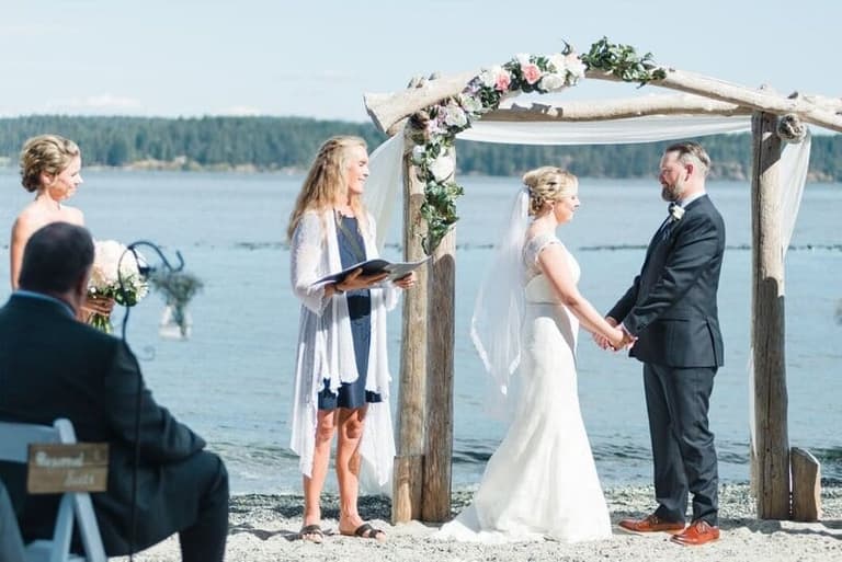 Life-Cycle Ceremonies officiant leading vows under a driftwood beach arbour