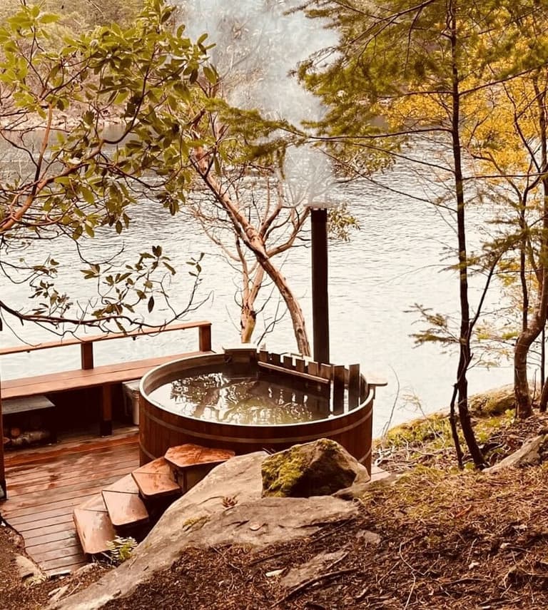 Wood-fired hot tub overlooking calm water at The Haven