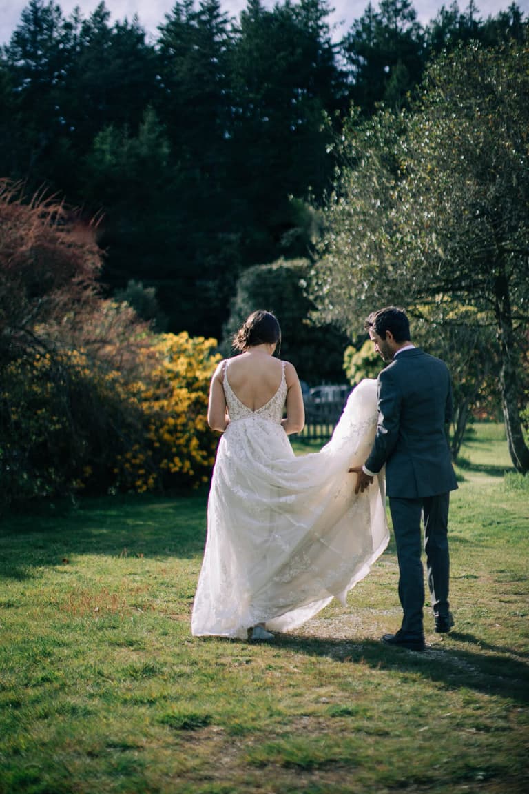 Groom lifting the gown's train on a garden path