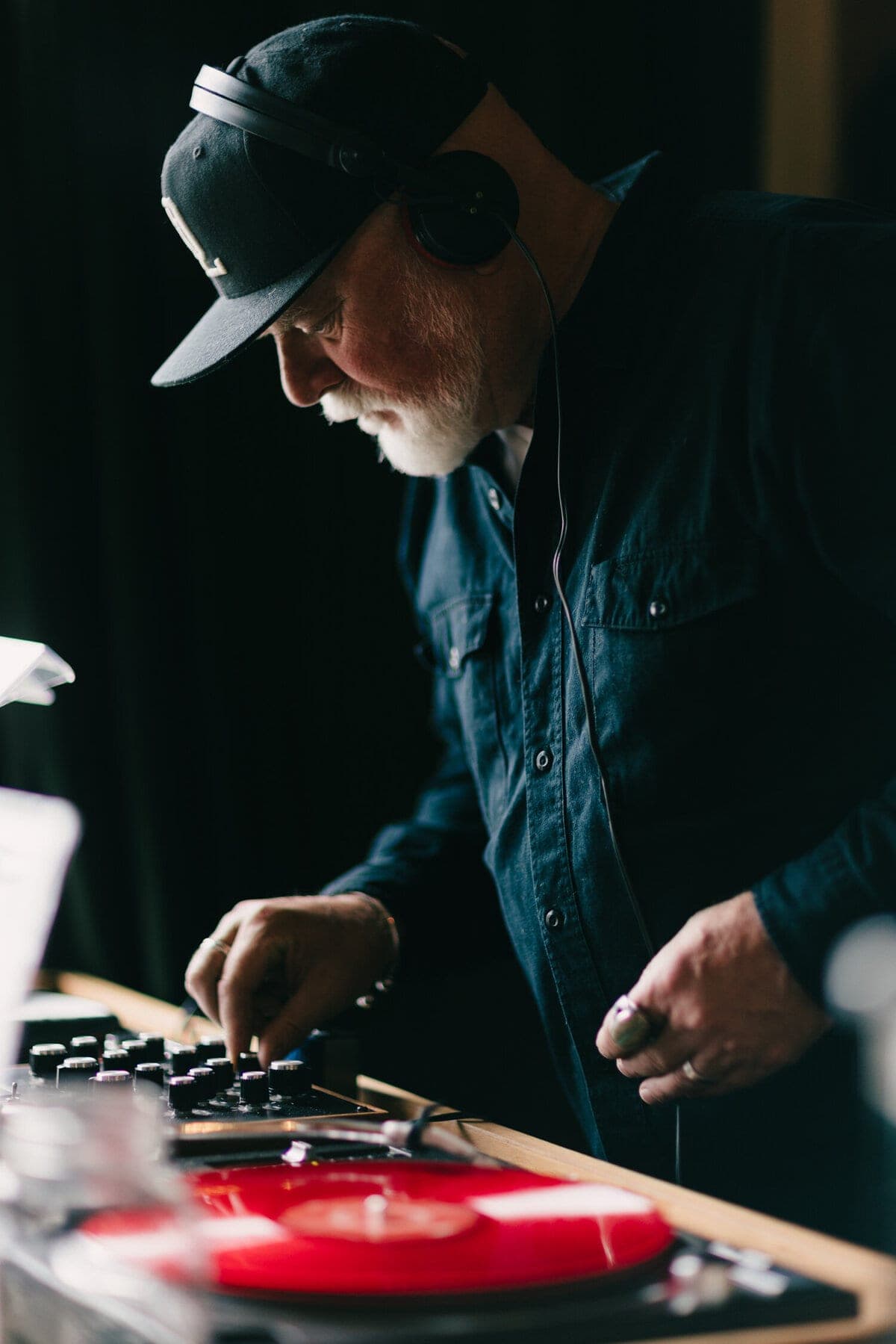 DJ Bassos adjusting mixer knobs over a red vinyl record
