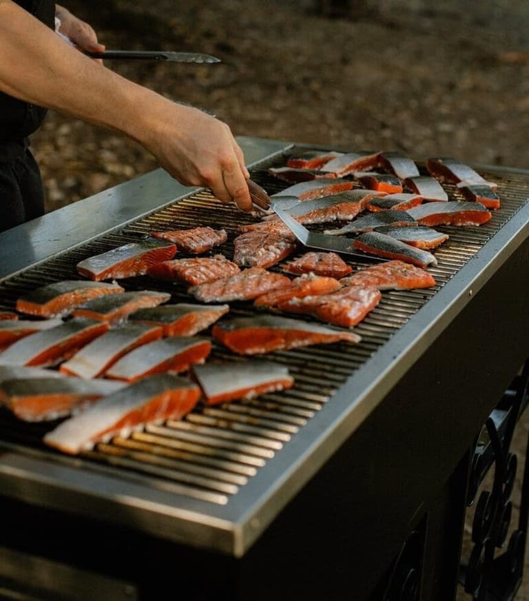Chef grilling wild salmon fillets by Ground Up Cafe and Catering