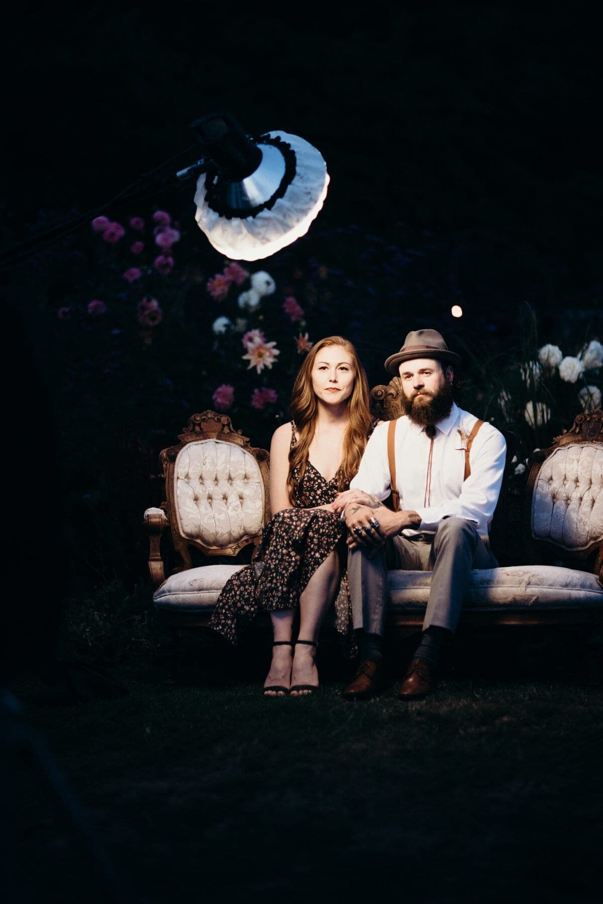 Couple posed on a vintage settee under studio light