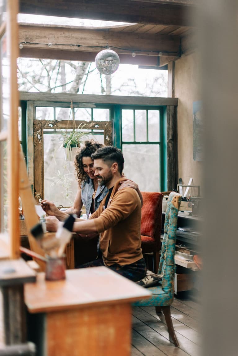Artist couple working side by side at an easel in their studio
