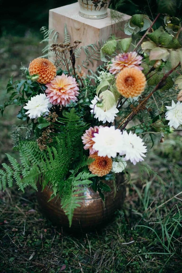 Dahlia and fern ceremony arrangement in a hammered copper vessel