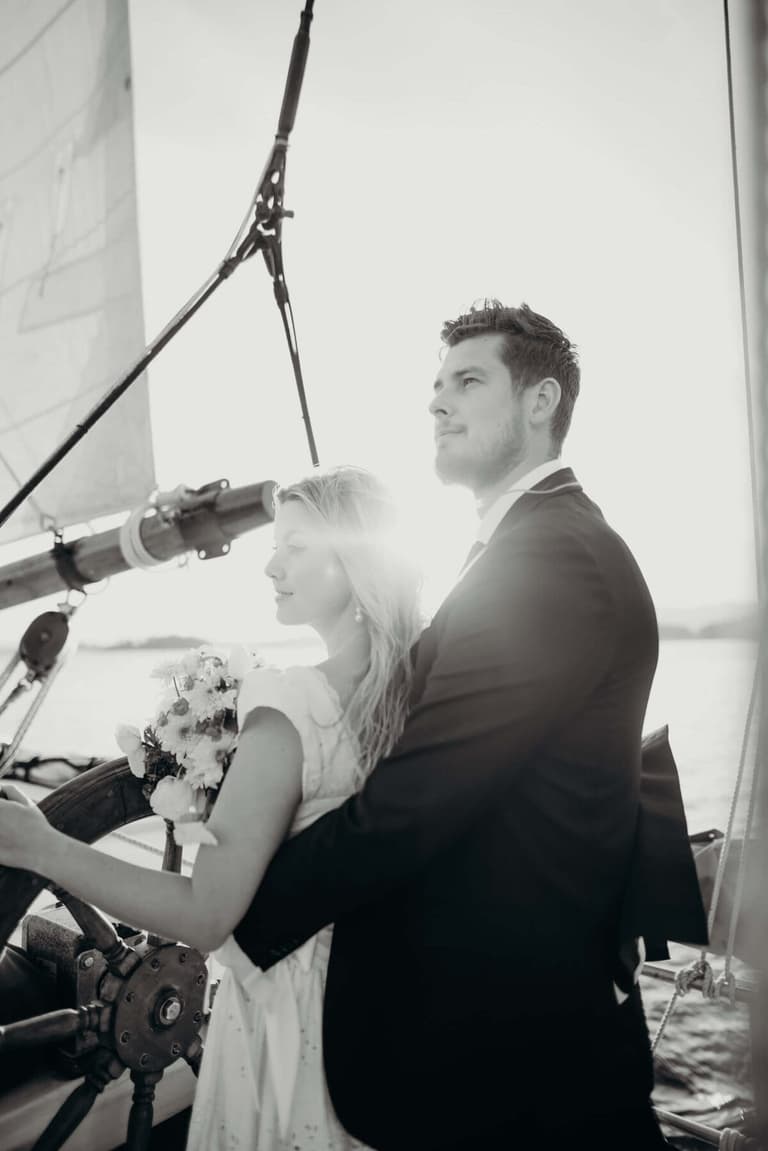 Sunlight flaring behind a couple steering the ship together