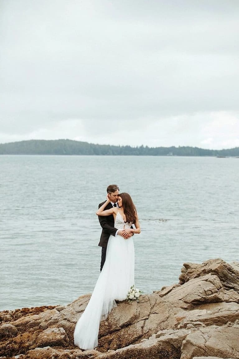 Couple embracing on oceanside rocks, captured by Melissa Renwick
