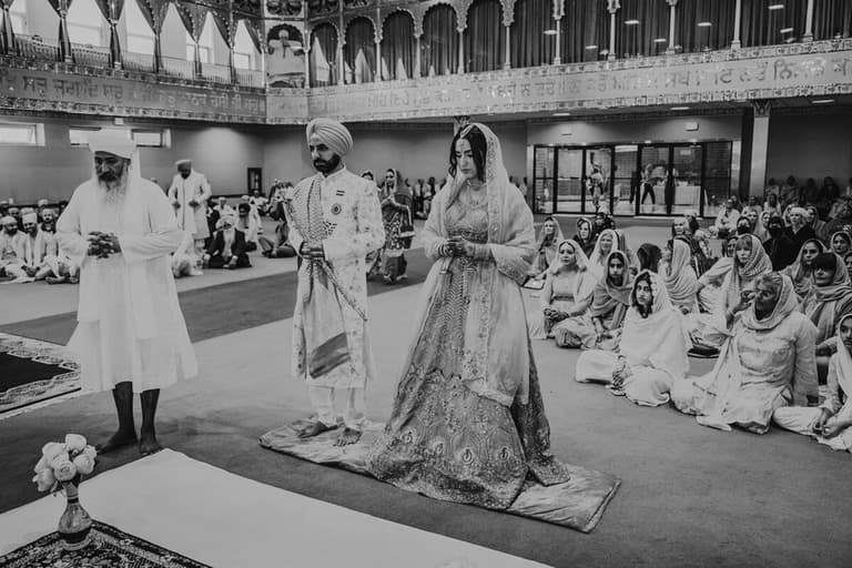 Sikh couple standing before the congregation in a gurdwara ceremony