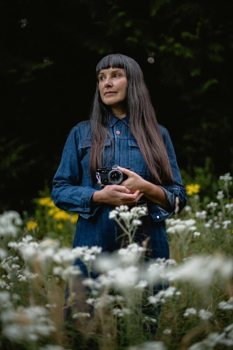 Photographer Stasia Garraway holding her camera among oxeye daisies
