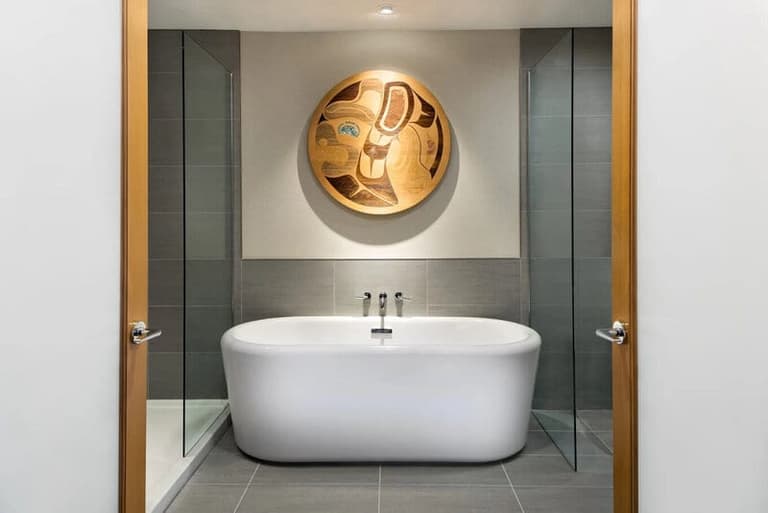Soaker tub beneath Indigenous cedar art at Kwa'lilas Hotel