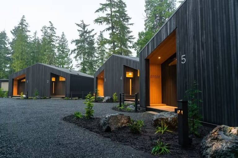Numbered charred-cedar suites among firs at Calmwater Retreat