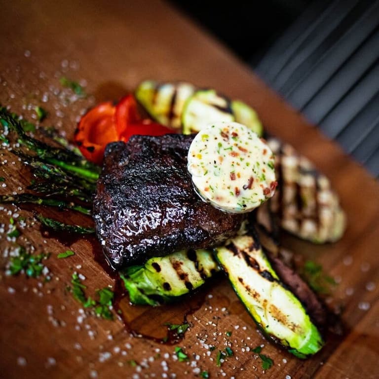 Grilled steak with herb butter and vegetables by Woodfire Restaurant