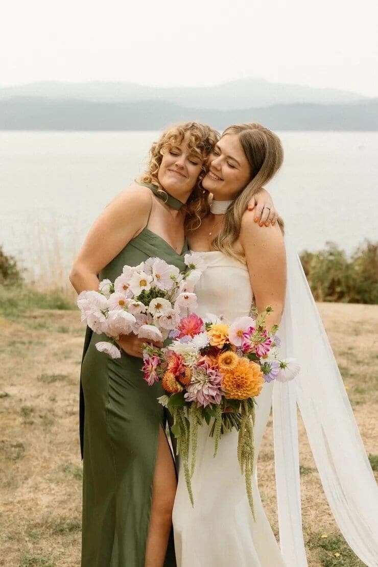 Bride and bridesmaid embracing with vivid Avalon Flower Farm bouquets