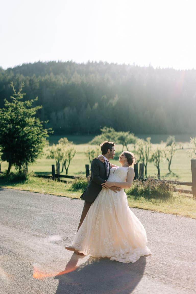 Couple dancing on a sunlit lane, gown sweeping the pavement