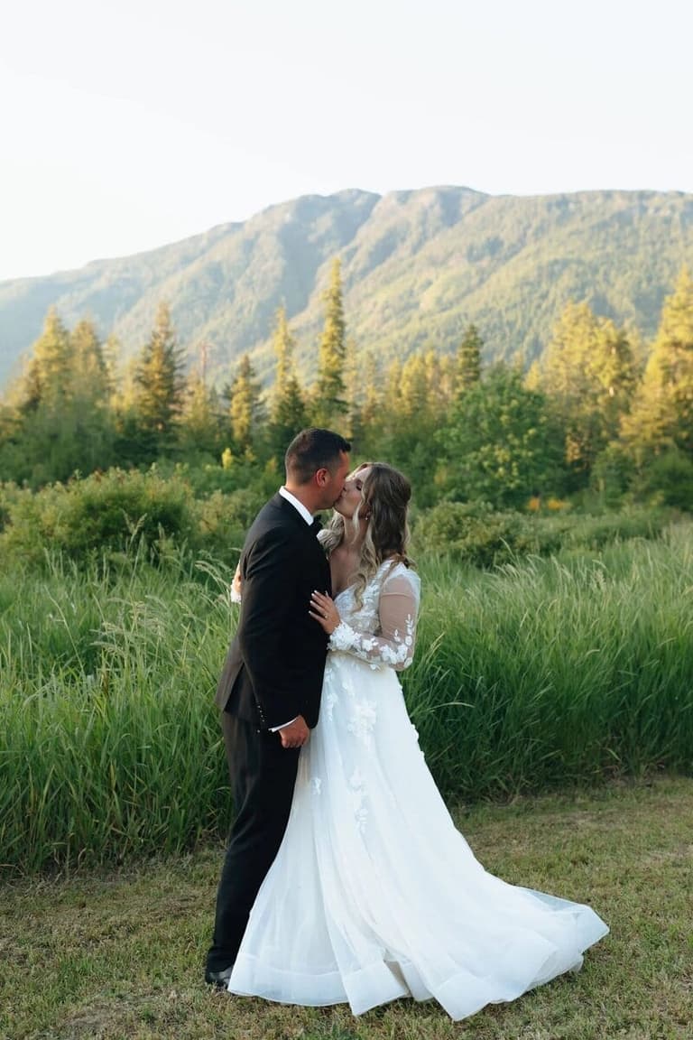 Newlyweds kissing in a tall grass meadow at Solstice Farm
