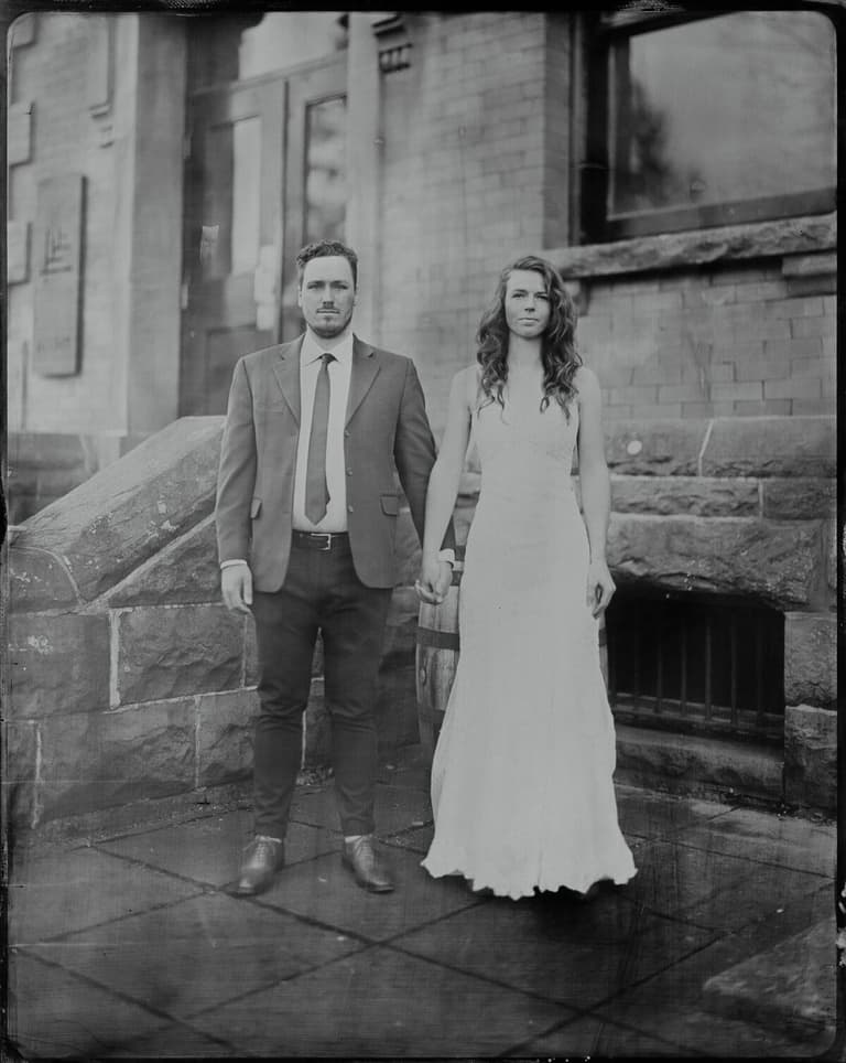 Tintype of a couple holding hands outside a stone building