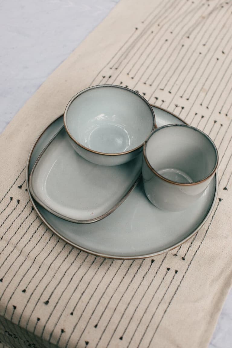 Blue-grey ceramic dishware stacked on a woven linen runner