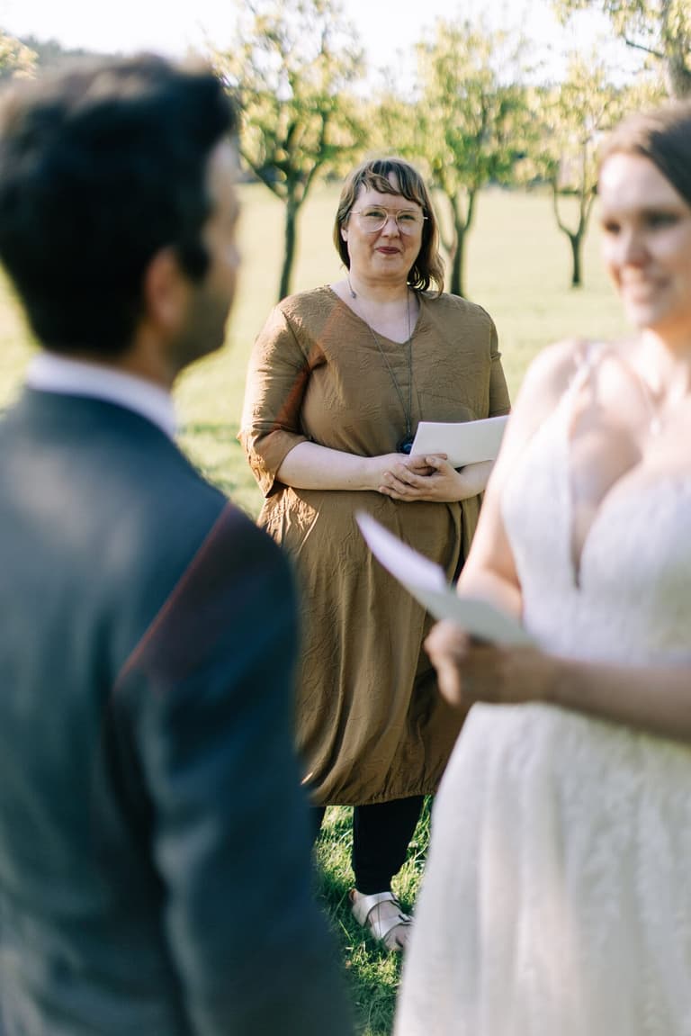 Officiant smiling as the couple exchange vows in the orchard