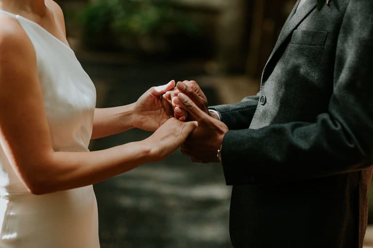 Close-up of a couple's clasped hands during their vows