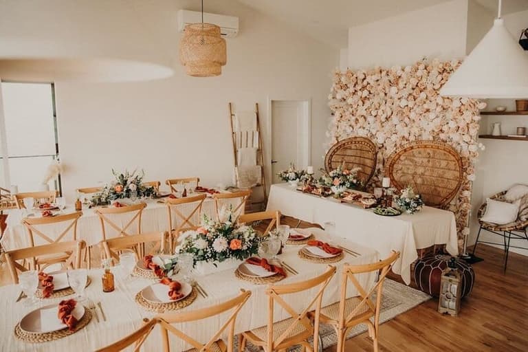 Peacock chairs and flower wall styled by Timeless Party Rentals