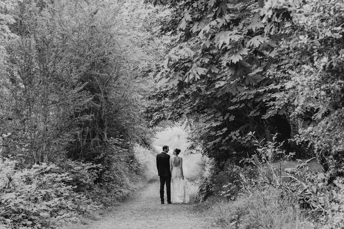 Couple walking a tree-arched path in black and white