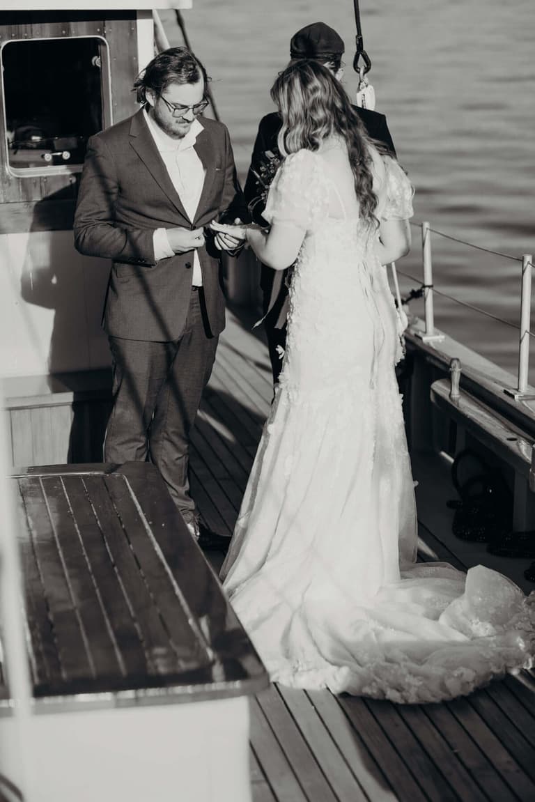 Man in a suit reading vows to the bride at the stern