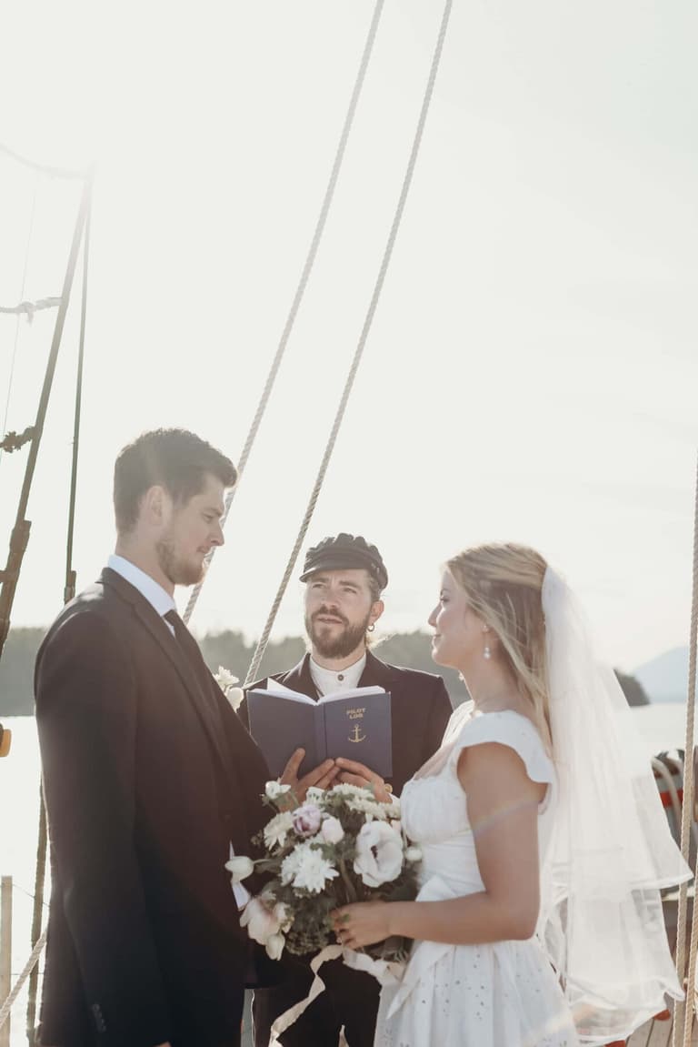 Captain in a fisherman's cap officiating a shipboard vow exchange
