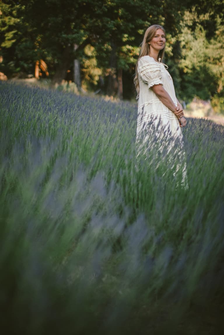 Bride in cream standing among blooming lavender rows at dusk