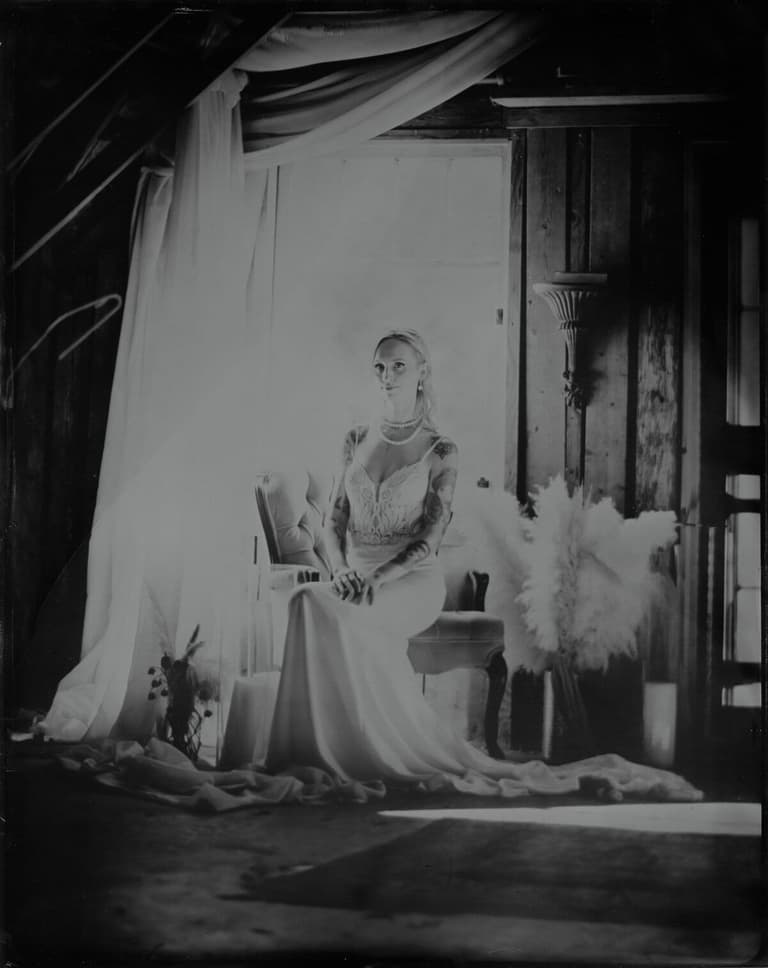 Tintype of a bride seated among draped linens and pampas grass
