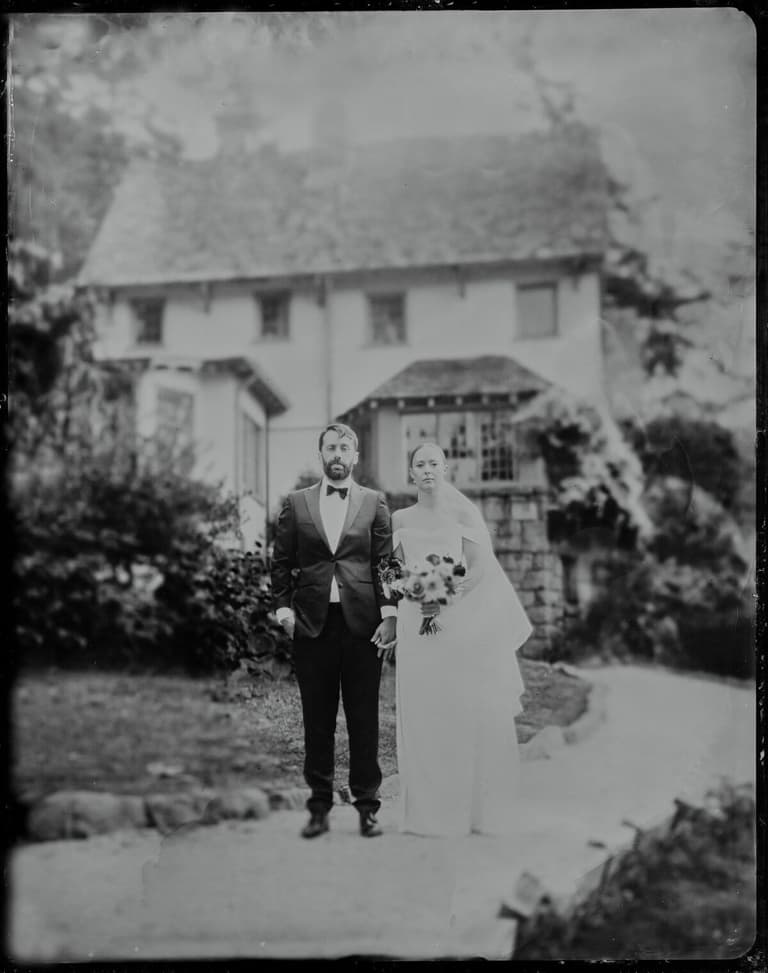Formal tintype of a couple before a storybook stone house