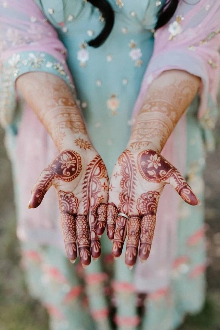 Open palms showing intricate bridal henna by Mehndi Nomadic