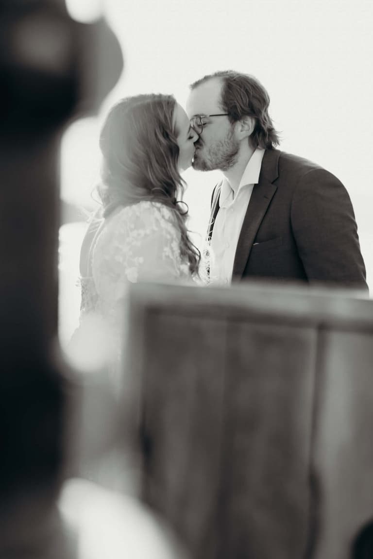 Couple stealing a kiss behind the wheelhouse, in sepia tones