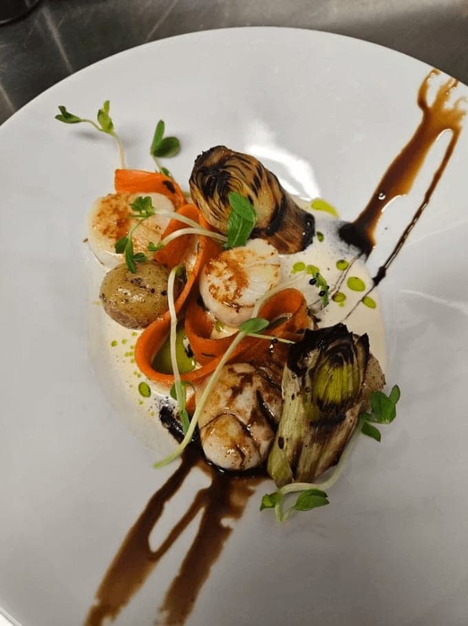 Seared scallops with charred leeks plated by Embers and Atlas