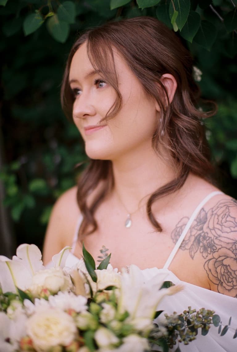 Flower-crowned bride and suspendered groom in a sunlit forest meadow